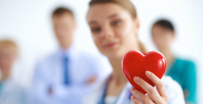 Female doctor with stethoscope holding heart